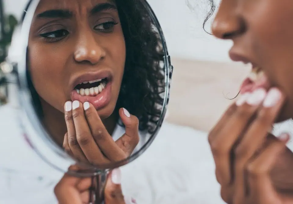 Woman looking in the mirror at her teeth.