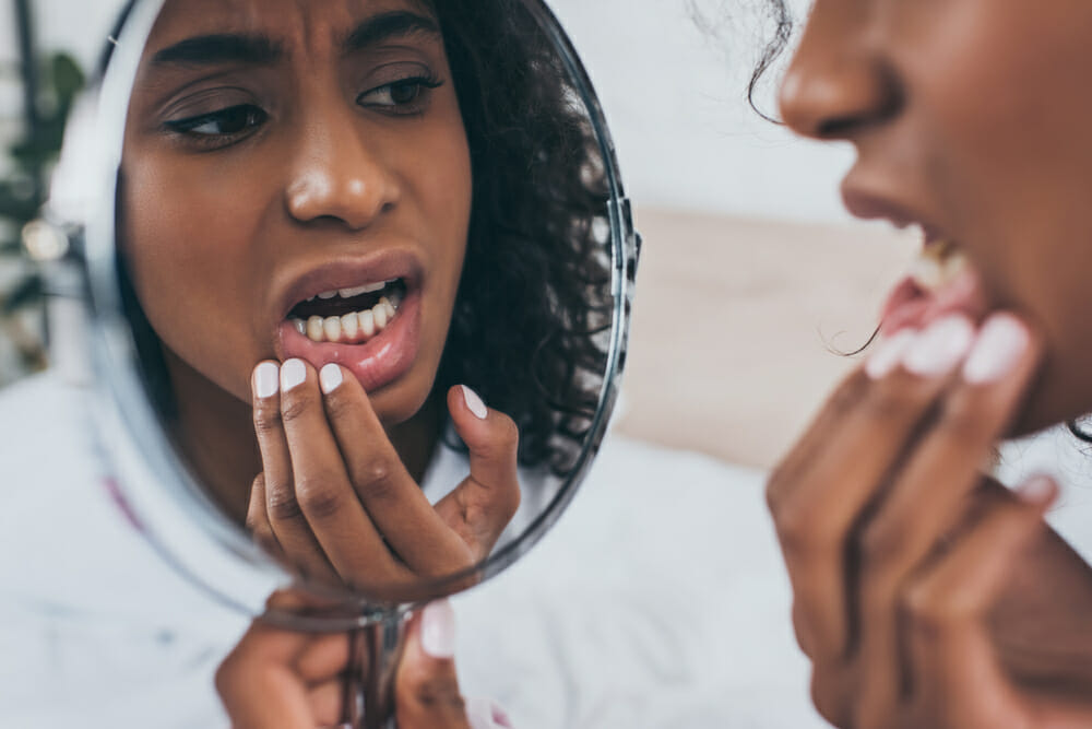 Woman looking in the mirror at her teeth.