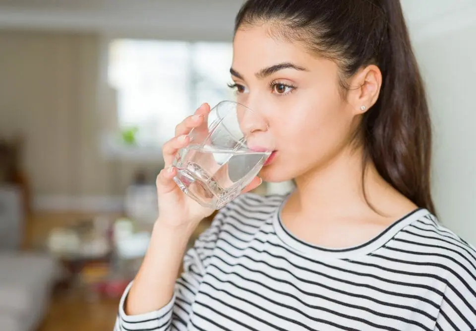 young woman with dry mouth drinking a glass of water
