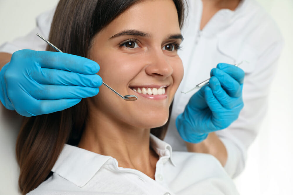 Woman Smiling with Dental Tools by Her Face