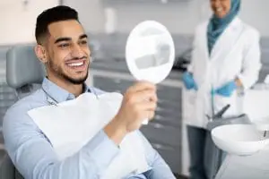 male looking at his teeth in a dental mirror